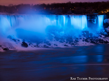 On the winter evening, Niagara Falls glows blue