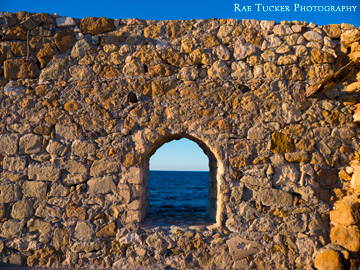 A window in a stone wall overlooks the Aegean Sea on the island of Crete