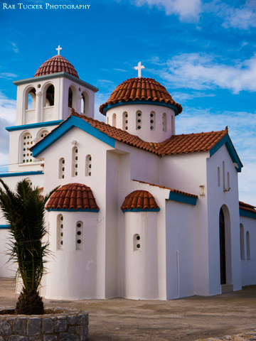 A Greek Orthodox Church stands out against the blue, winter sky by the port in Kissamos, Crete