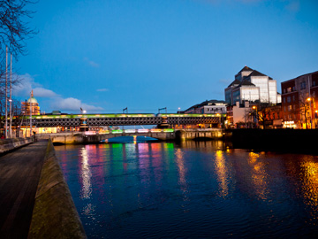 The River Liffey is illuminated by the lights of Dublin at dusk.