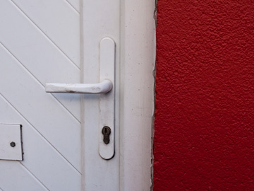 A white door with handle on a red building