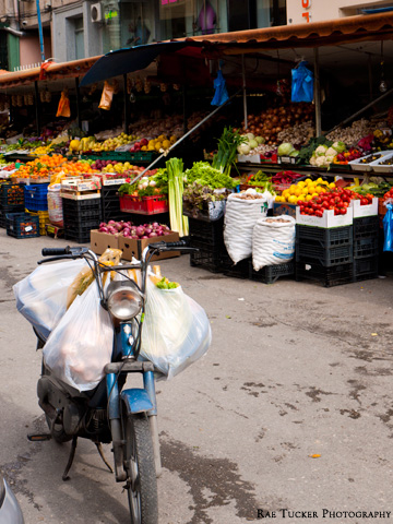 A small moped is loaded with bags of produce by a market in Tirana, Albania