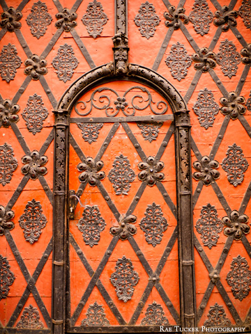 An ornate, red, metal door in Prague, Czech Republic.