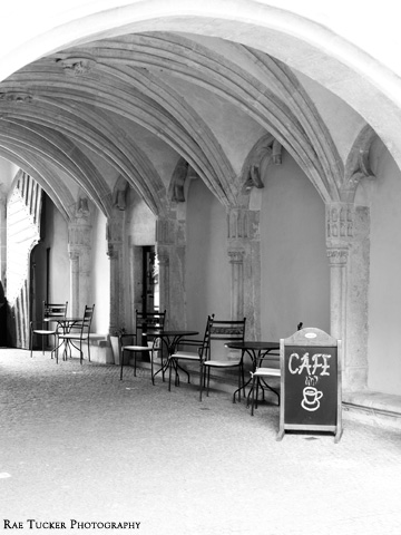 A black and white image of a cafe patio under an arcade in Bratislava, Slovakia