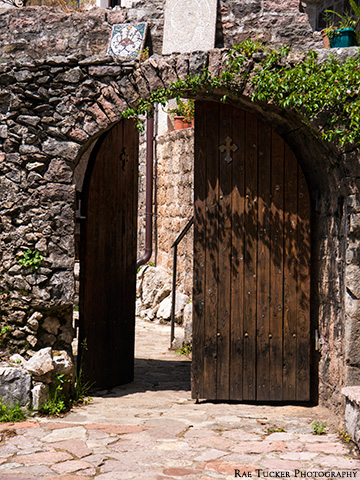Arched, wooden doors lead to Podmaine Monastery in Budva, Montenegro