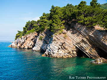 In Petrovac, Montenegro, tree topped cliffs meet the blue sea.
