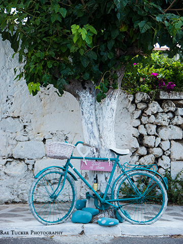 In Paleochora, a blue and white bicyle leans against a tree.