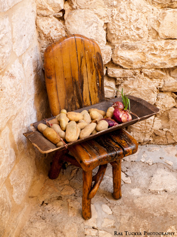 A wooden chair holds a wooden tray with fresh vegetables in Trogir, Croatia