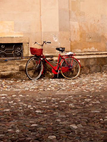 A red, old-fashioned bicycle leans agains a wall in Bolzano, Italy