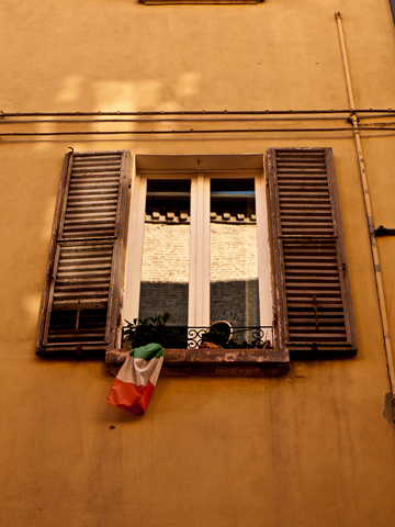 A window in Modena, Italy adorned with an Italian flag.