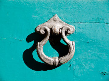 An old style door knocker on a turquoise door in Cortona, Italy