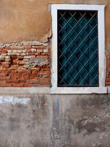 Various textures are displayed on this wall and window in Venice, Italy