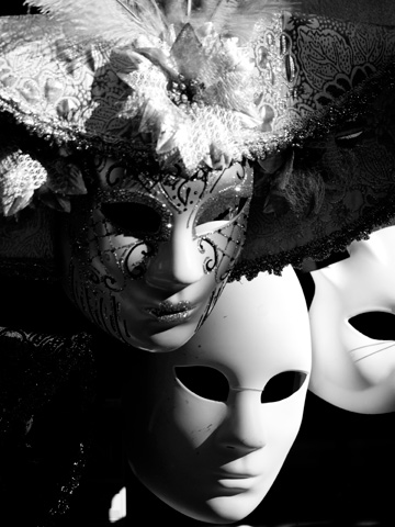 A black and white image of dramatic carnival masks in Venice, Italy
