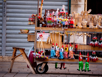 A vendor's wooden products, such as Pinocchio toys is displayed on a wooden cart in Venice, Italy