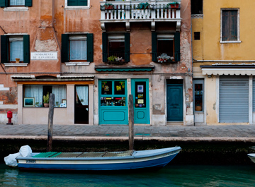 A blue boat and colorful doors along a canal in Venice, Italy