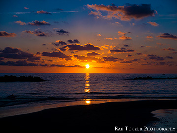 The sun descends along the horizon over the blue waters of the Tyrrhenian Sea in Anzio, Italy.