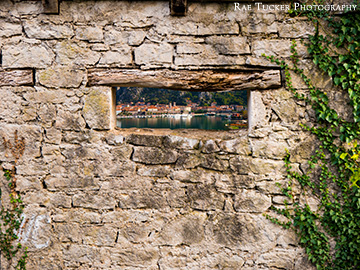 Through the small window of an old stone building, the stari grad, or old town, or Kotor, Montenegro can be seen.