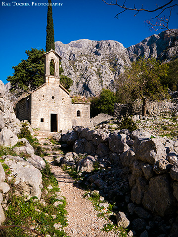 A path leads through the ruins of a town towards Saint John Church in Kotor, Montenegro.
