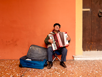 An man plays the accordion while busking in Bologna, Italy