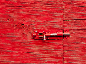 A red door held in place by a small latch