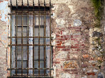 A barred window on a textured wall in Viareggio, Italy