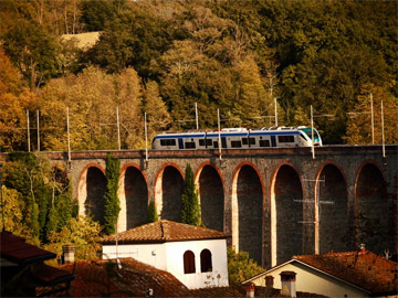 A small commuter train travels through the Tuscan countryside.
