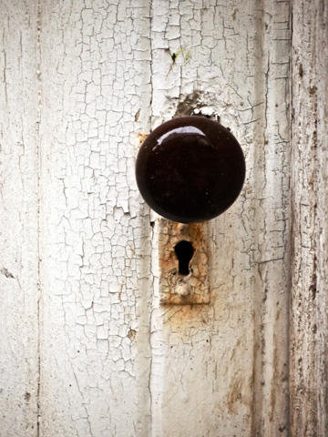 The small, round handle of a white door